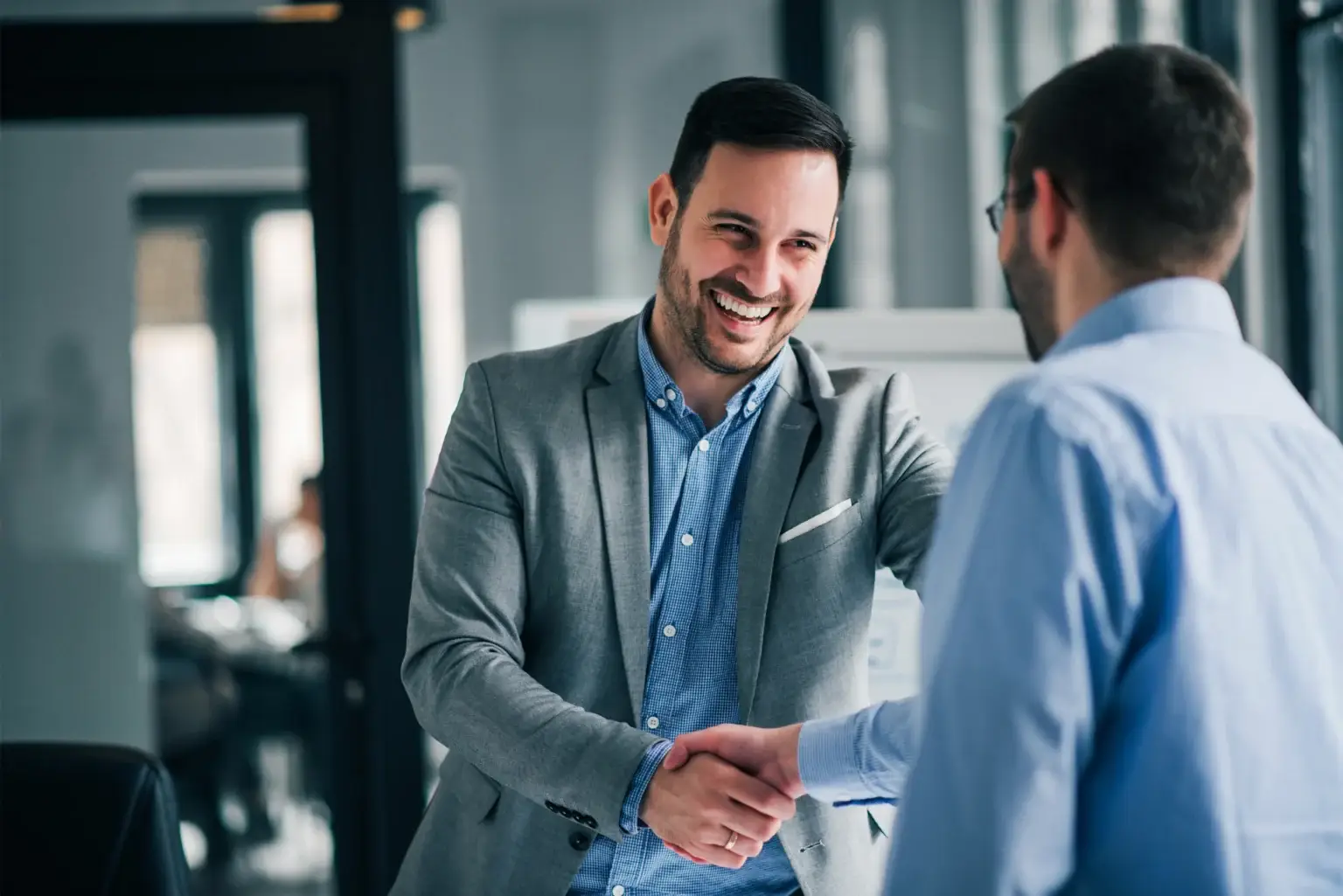 Deux hommes se serrent la main avec un sourire.